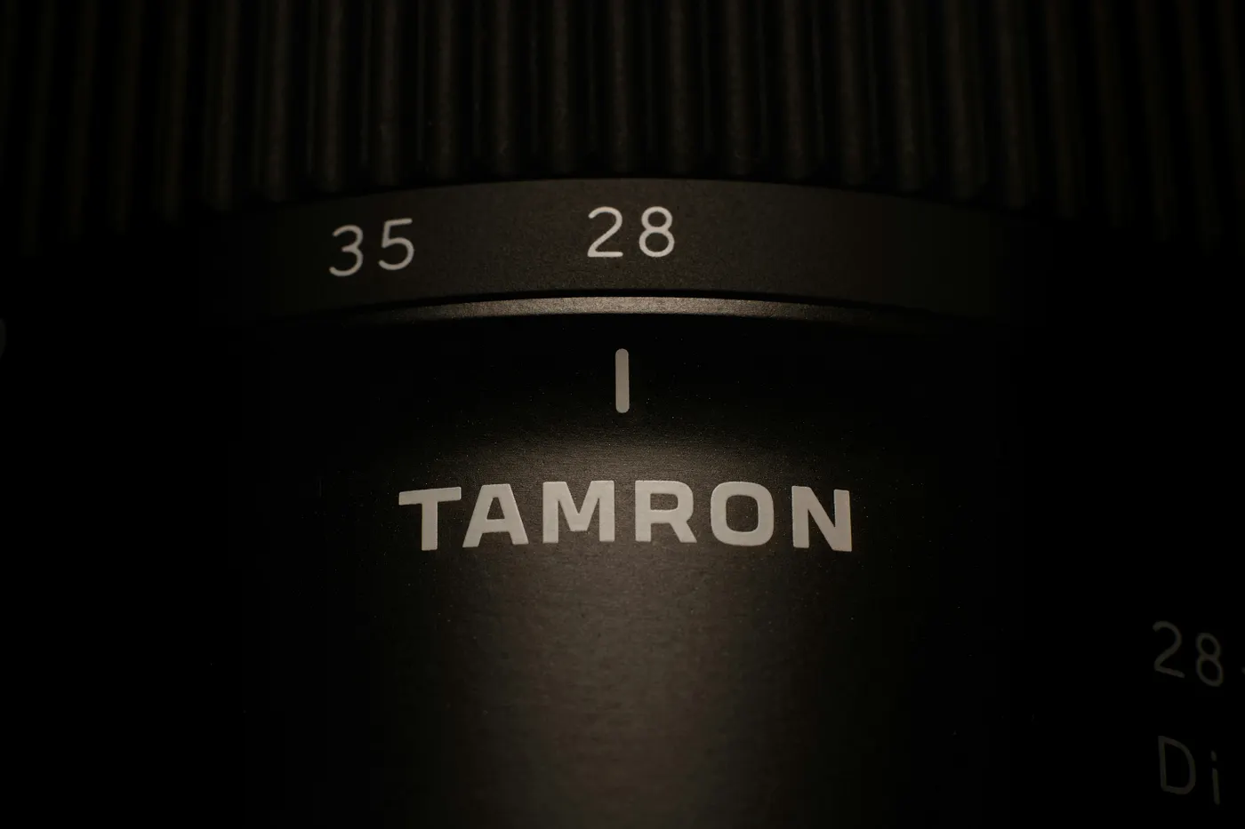 Close-up of a black Tamron camera lens with zoom at 28mm, and 